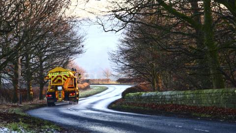 Council gritter spreading salt on a rural road in Wharfedale Yorkshire England UK