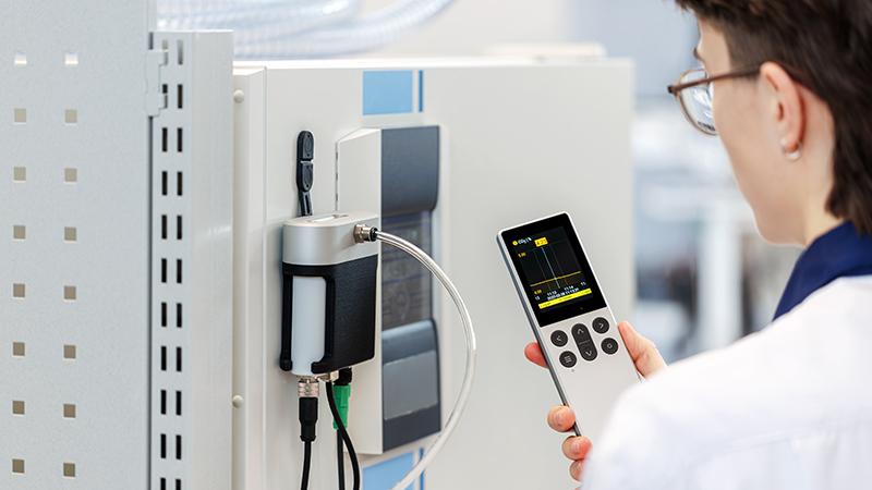 Person holding handheld instrument next to incubator
