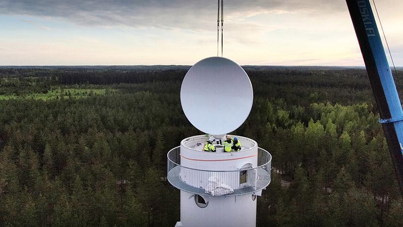 Maintenance to weather equipment on top of a tower in landscape.