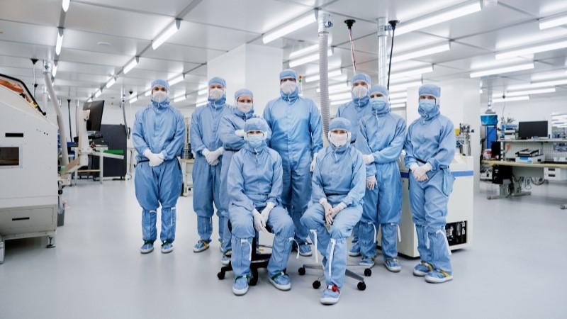 Group photo of people in protective gear in a cleanroom
